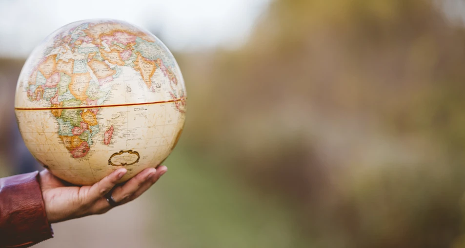 persona en medio de un camino sosteniendo un globo terraqueo