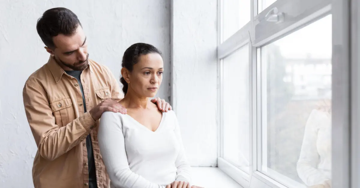 mujer triste mirando por la ventana junto con su esposo